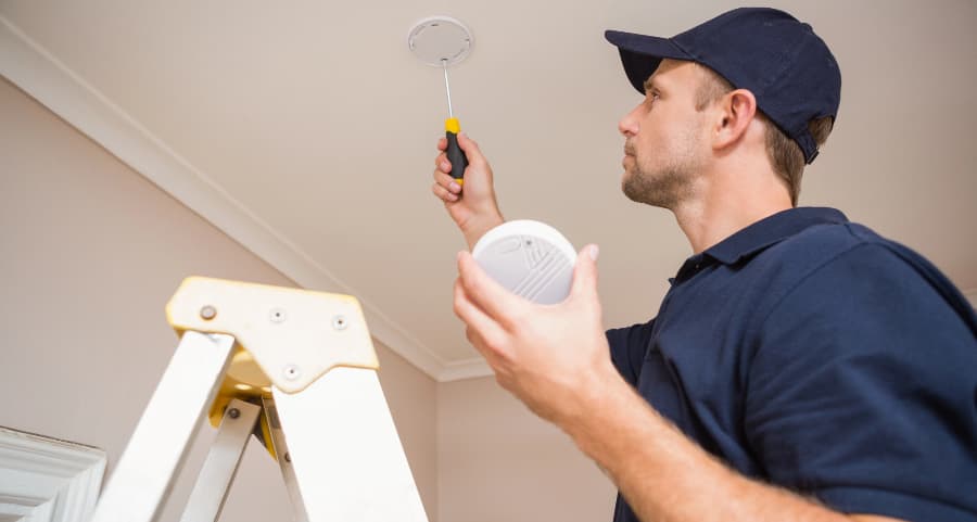 Man installing smoke detector on ceiling